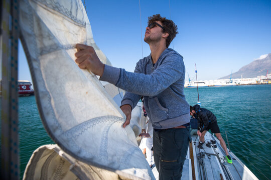Young man on yacht working with sail rigging on the ocean