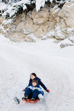 Siblings sledding downhil