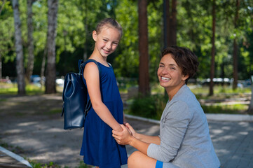 Fototapeta premium Caucasian woman gathers her first-grader daughter to school
