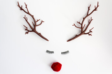 Christmas reindeer concept with red nose and antlers and eyelashes on white background