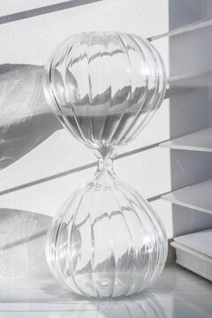 An hourglass sand timer on a window ledge in bright sunshire