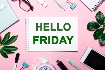 Fototapeta na wymiar HELLO FRIDAY written on a pink background near green leaves and business accessories. Motivational concept