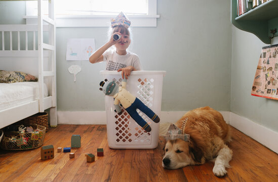 Child playing in laundry hamper with newspaper hat