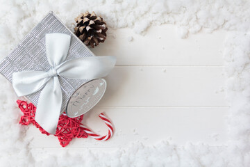 Top view of gift box and christmas decoration on white wooden table with snow and copy space