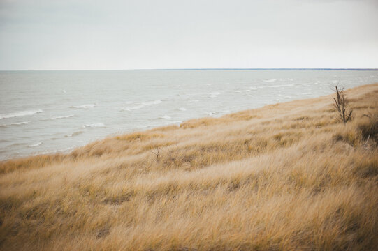 Sand dunes on beach by wavey lake on cold windy winter day