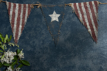 Small white blooms, rustic star and strips banner on a blue gray textured background.