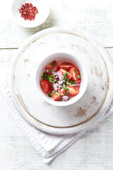 Simple salad with cherry tomatoes, red onion and fresh herbs. Bright wooden background. Top view.