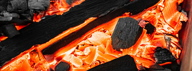 Close-up of actively smoldering embers. Red live coals in burning fire. Bonfire on street. Flame...