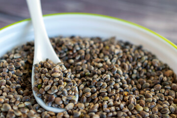 close up of cannabis seeds in ceramic dish on wooden table.