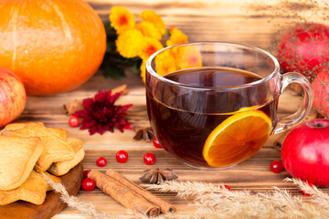 Autumnal cup of tea on a rustic wooden table with cinnamon, anise stars and lemon. Pumpkin, autumn flowers, apples.