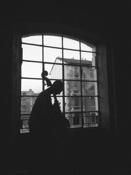 Man playing contrabass against a window