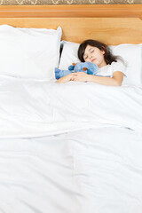 Obraz na płótnie Canvas girl is sleeping with a soft toy on white bed