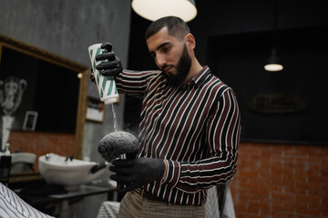 Barbershop workshop stylish design. the haircut master applies a talik to the head of a dark-haired client, with a large brush. favorite work