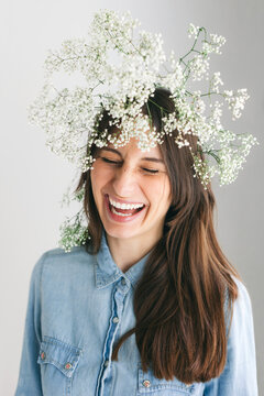 Young woman laughing with gypsophila paniculata on head.