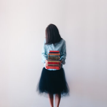 Movement image (intentionally blurred) of unrecognisable woman holding a stack of books
