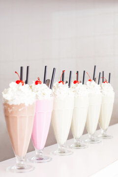Six milk shakes in row on a white table.