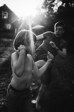 Two boys play fighting at dusk.