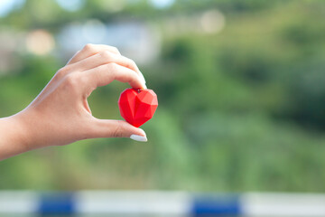 woman holding red heart in nature