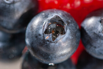 Close-up blueberry and red raspberry on a mirror surface