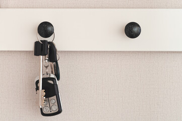 A bunch of modern keys hangs on a clothes hook in the hallway. Closeup.