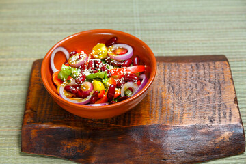 Clay Plate with Pan-Asian salad with sesame seeds and tamarind on wooden stands.