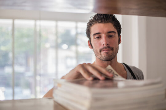 Handsome male student picking a magazine in a library