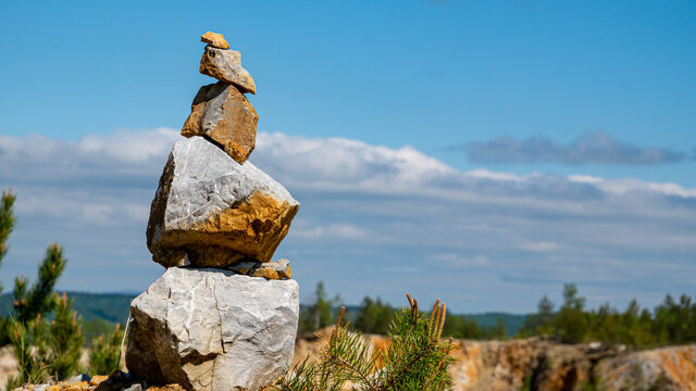 Stack of stones with clouds and blue sky in the background.