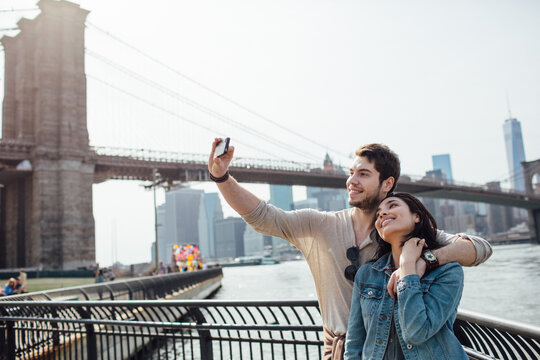 Smiling couple taking a selfie with Manhattan on the background