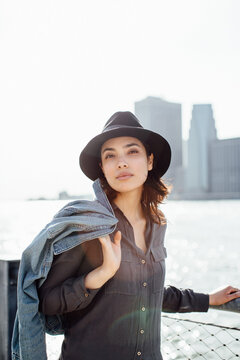 Portrait of young attractive woman with hat holding her jeans jacket