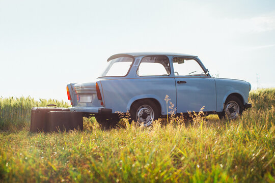 Two Leather Suitcases Standing Next to Blue Vintage Car on Sunny Summerday