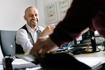 Happy businessman looking at documents presented by colleague