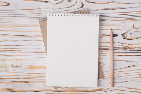 Blank page of sketch pad, pencil and pen on wooden table top view. Summer  travel journal or art book banner background Stock Photo