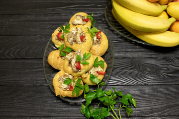 Profiteroles stuffed with cream cheese, onions and mushrooms close up on wooden background. Selective focus