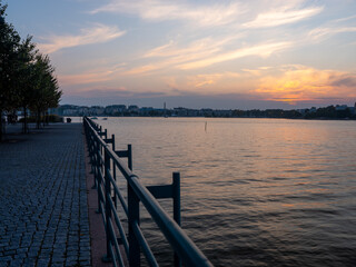 A beautiful sunset: View from the riverbank towards city skyline with calm waters on a summer night.