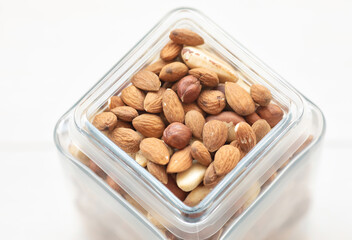 Assorted nuts in a glass jar walnut, brazil nut, pecan, pistachios, almond, macadamia, peanut, cashew, hazelnut.