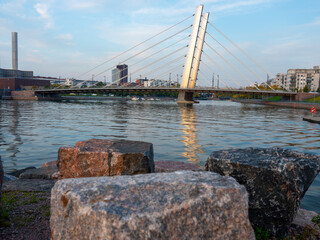 A beautiful sunset on the river bank with calm waters on a summer night. A city skyline with a modern cable bridge.