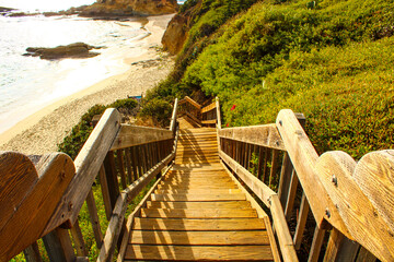 a wooden staircase down a hill to a beach with lush green hills and sandy beaches at the Pirate Tower at Victoria Beach in Laguna Beach California © Marcus Jones