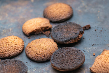 Burnt cookies. Burnt, burnt oatmeal cookies lie on a black baking sheet.