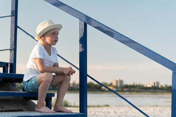 Boy sits alone on the stairs in beach background. Holidays