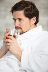 handsome man drinking tea and relaxing in bathrobe