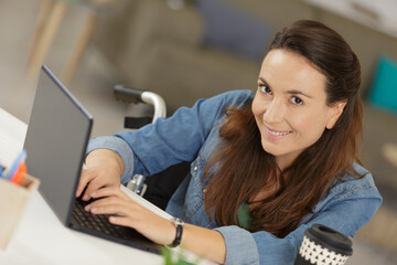 happy disabled woman in wheelchair with laptop