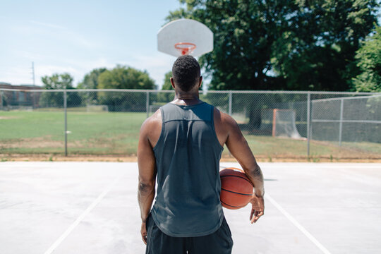 Athletic African-American man playing basketball outside