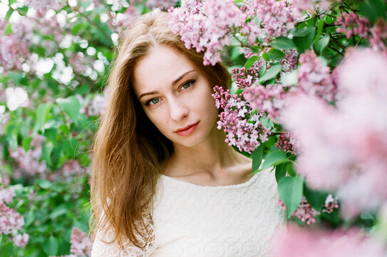 Portrait of redhead woman among pink lilac