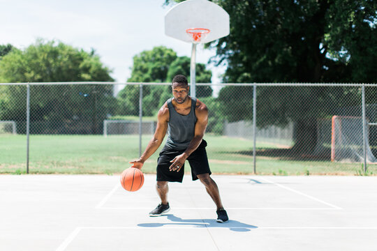 Athletic African-American man playing basketball outside