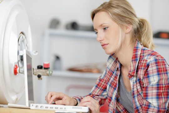 charming adult girl in shirt near boiler control panel