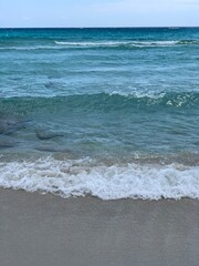 Fototapeta na wymiar Blue and lazur aquamarine waves on the sand beach in Aiya Napa in Cyprus 