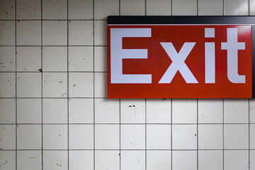 Red Exit Sign on a Weathered White Wall