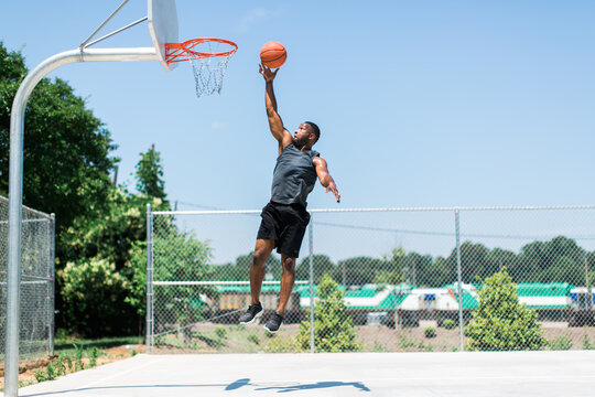 Athletic African-American man playing basketball outside
