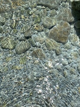 Sun rays on sea water. Pebbled seabed of the Adriatic. Crystal clear water of Mediterranean sea. Sea pebbles and stones. Summer vacation on Montenegro. Health and relaxation. Pure transparent water.