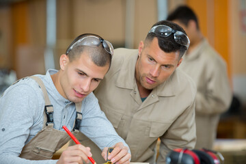 young apprentice with teacher working with wood